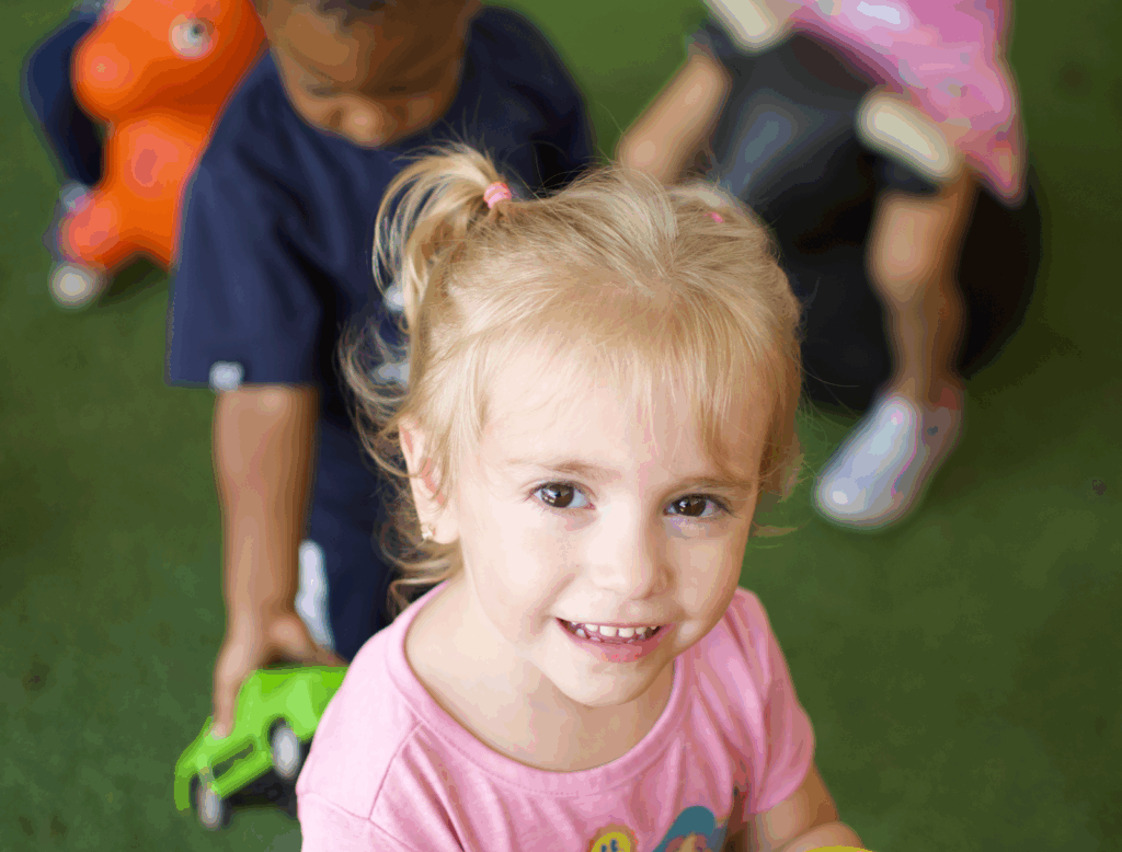 Smiling toddler enjoying outdoor activities at Tiny People University Childcare Center in Magnolia, TX. 